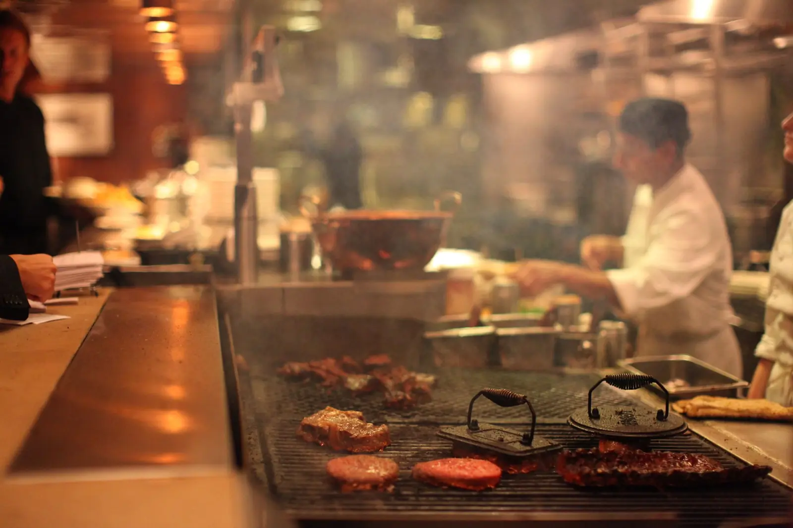 Köche am Grill in einer vollen Restaurantküche während des Service